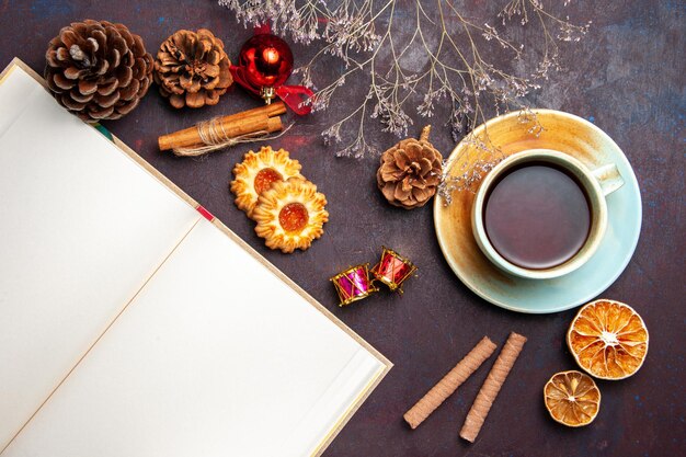 Vista superior de una taza de té con galletas en el espacio oscuro