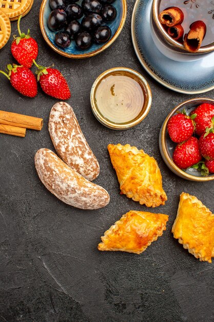 Foto gratuita vista superior de la taza de té con galletas y frutas en el escritorio oscuro pastel de frutas de galletas dulces