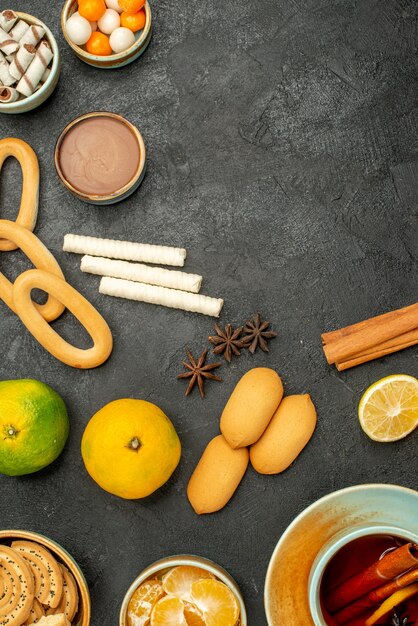 Vista superior taza de té con galletas y frutas en el escritorio oscuro pastel galleta té galleta