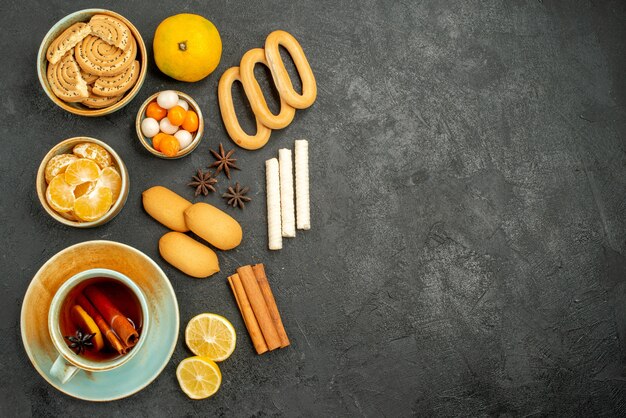 Vista superior de una taza de té con galletas y frutas en el té de la galleta de la torta de la galleta de la mesa oscura