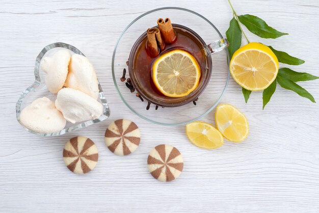 Vista superior de una taza de té con galletas de limón y canela en blanco, dulces de postre de té