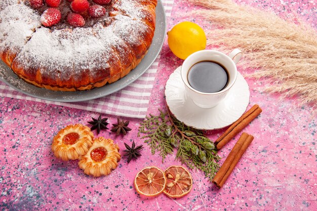 Vista superior de una taza de té con galletas, limón, canela y pastel en el escritorio rosa galleta galleta pastel dulce