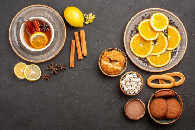 Vista superior de una taza de té con galletas y naranjas frescas en rodajas sobre una superficie oscura galleta de galletas cítricas de frutas