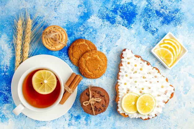 Vista superior de la taza de té galletas de pastel de árbol de Navidad atadas con galletas de cuerda en la mesa azul