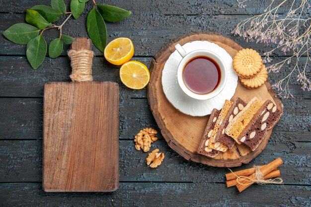 Vista superior de una taza de té con galletas y pasteles en el azúcar de tarta de galletas dulces de mesa oscura