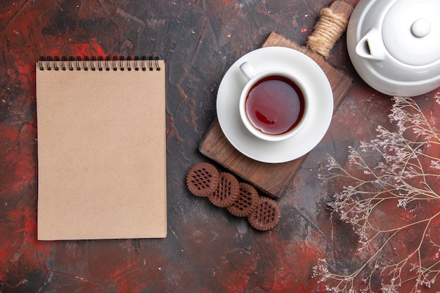 Vista superior de una taza de té con galletas en el piso oscuro