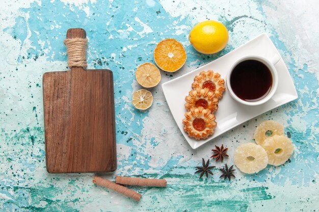 Vista superior de una taza de té con galletas en la superficie azul claro