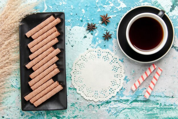 Vista superior de una taza de té con galletas en la superficie azul