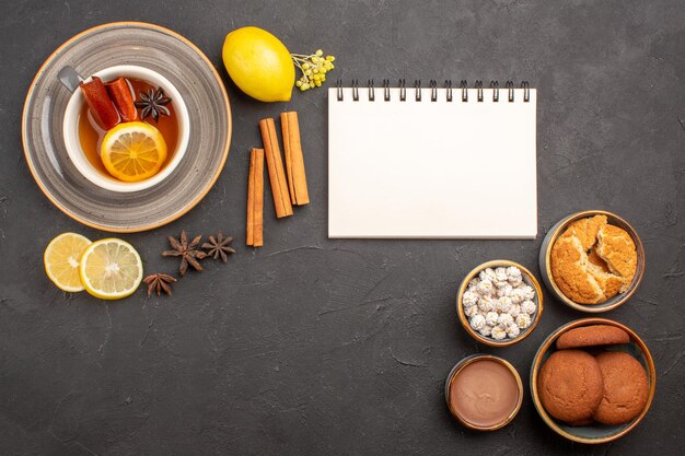 Vista superior de la taza de té con galletas en la superficie oscura dulce de galletas de frutas de té