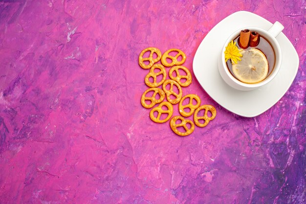 Vista superior de la taza de té con galletas en el té de color rosa caramelo de limón de mesa