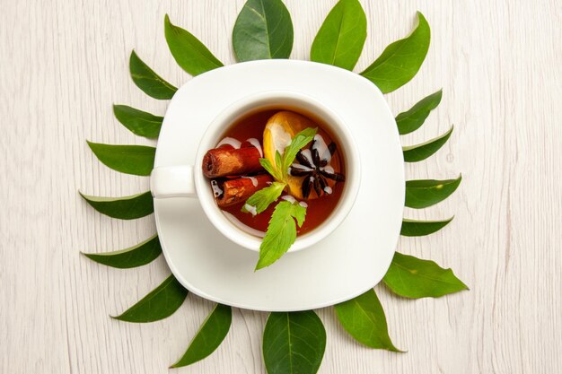 Vista superior de la taza de té con hojas verdes en la ceremonia de la fruta del té de color de escritorio blanco