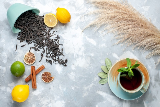 Vista superior de la taza de té con limón y canela en la mesa de luz, té de frutas cítricas de color seco