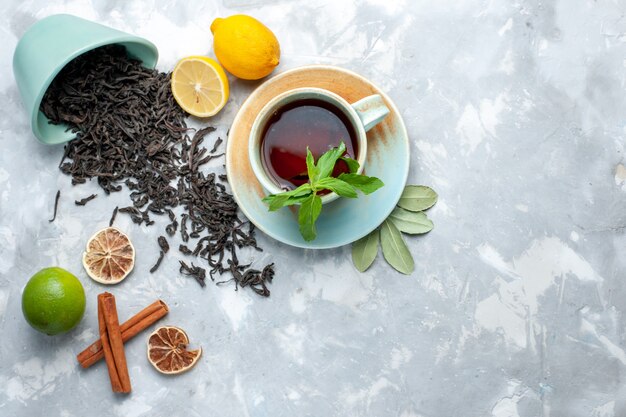 Vista superior de la taza de té con limón y canela en la mesa de luz, té de grano de cítricos de color seco