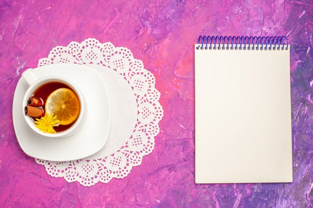 Vista superior de la taza de té con limón y canela en la mesa rosa té color caramelo