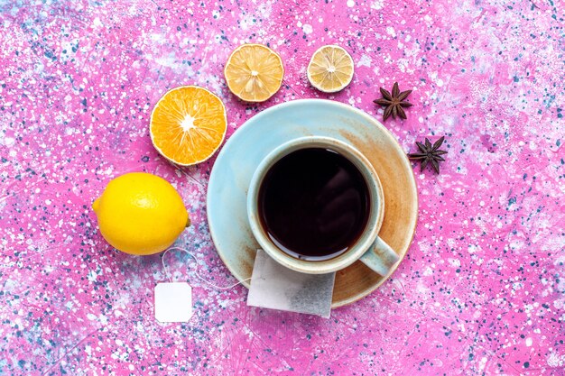 Vista superior de una taza de té con limón en el escritorio rosa.