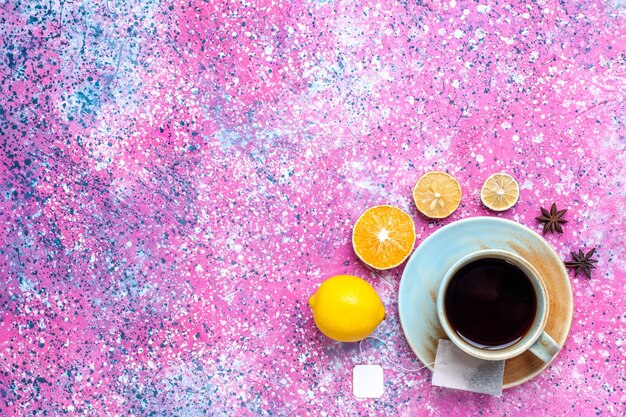 Vista superior de una taza de té con limón en el escritorio rosa.