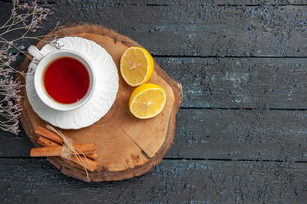 Vista superior de una taza de té con limón en la mesa oscura