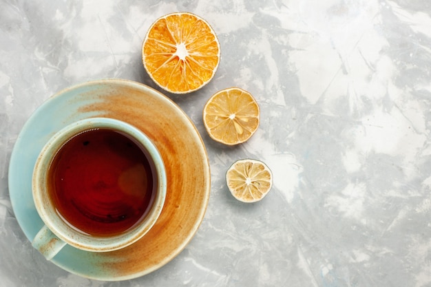 Vista superior de la taza de té con limón sobre superficie blanca