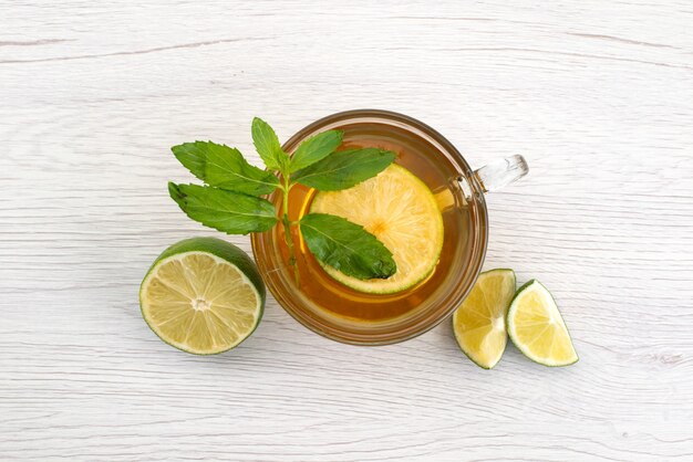 Vista superior de una taza de té con limón verde y min en blanco, agua de té de frutas