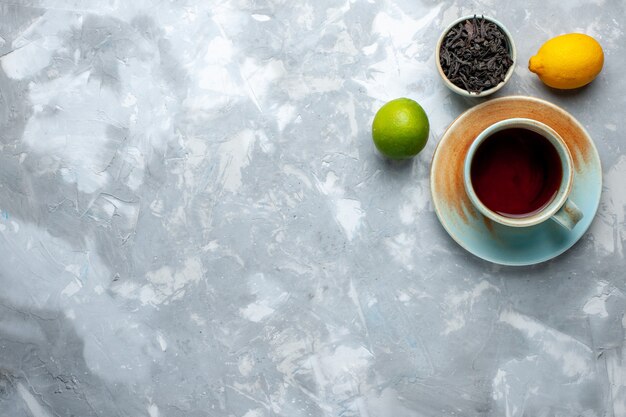 Vista superior de una taza de té con limones frescos y té seco en la mesa de luz, color cítrico de frutas de té