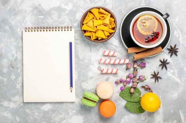 Vista superior de la taza de té con macarons franceses en el escritorio de color blanco claro