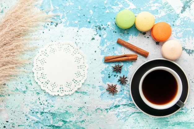 Vista superior de una taza de té con macarons franceses en la superficie azul