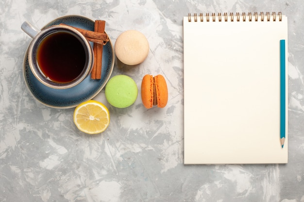 Vista superior de la taza de té con macarons en superficie blanca