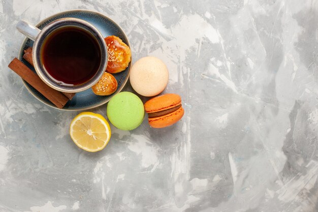 Vista superior de la taza de té con macarons en superficie blanca