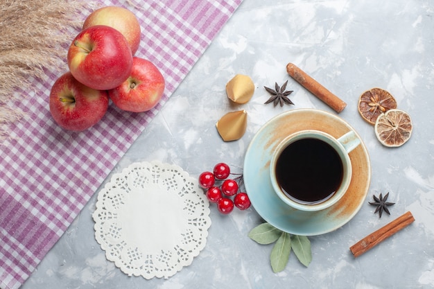 Vista superior de la taza de té con manzanas rojas canela y rodajas de limón seco en el escritorio de luz té color caramelo desayuno
