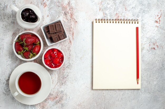 Vista superior de la taza de té con mermelada y chocolate sobre superficie blanca