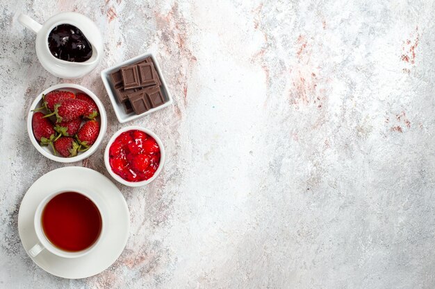 Vista superior de la taza de té con mermelada y chocolate sobre superficie blanca