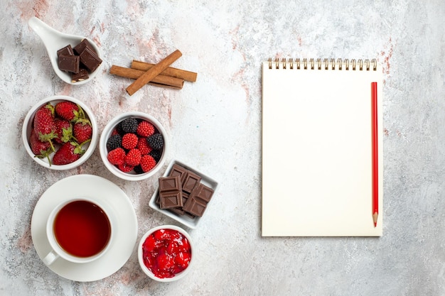 Vista superior de la taza de té con mermelada de fresas y confituras en superficie blanca