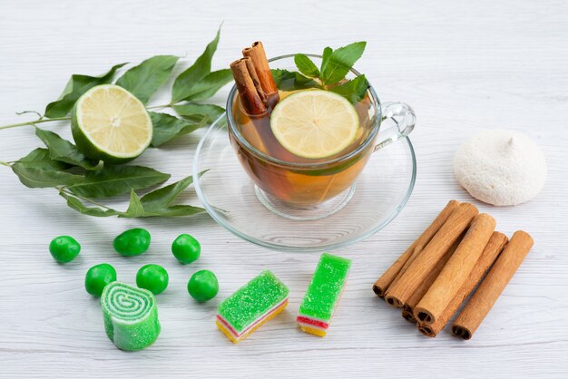 Vista superior de una taza de té con mermelada de limón y menta y canela sobre blanco, dulces de postre de té