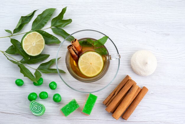 Vista superior de una taza de té con mermeladas de limón y canela sobre blanco, dulces de postre de té