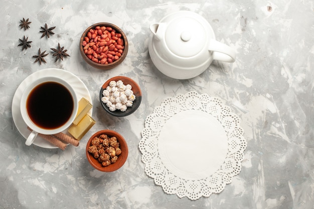 Vista superior de una taza de té con nueces y galletas en la superficie blanca