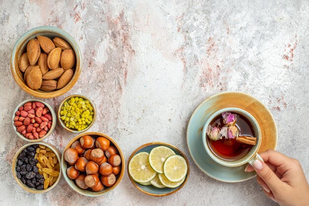 Vista superior de la taza de té con pasas, nueces y rodajas de limón en la superficie blanca bebida cítrica de té de frutas