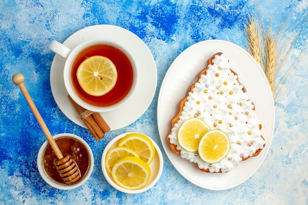 Vista superior de la taza de té pastel de árbol de Navidad en la placa rodajas de limón miel en un tazón sobre la mesa azul