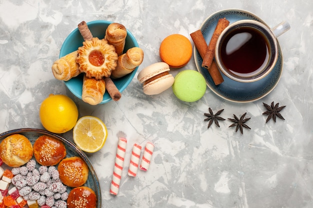 Vista superior de una taza de té con pasteles y macarons en la superficie blanca