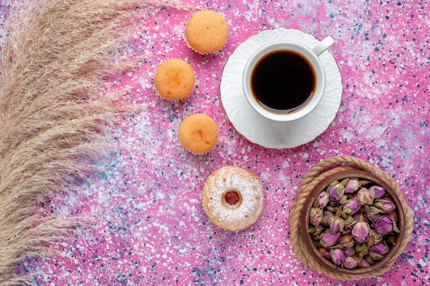 Vista superior de la taza de té con pasteles en superficie rosa