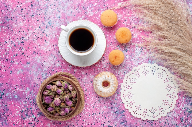 Vista superior de la taza de té con pasteles en superficie rosa