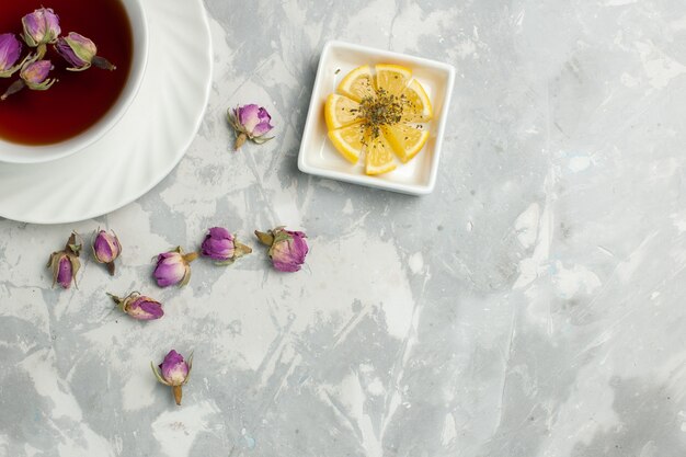 Vista superior de la taza de té con pequeñas flores en el escritorio de color blanco claro