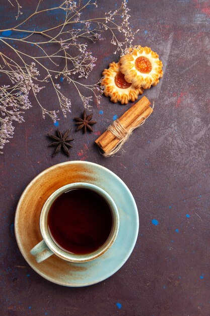 Vista superior de una taza de té con pequeñas galletas sobre fondo oscuro, galleta, galleta, pastel, azúcar, té