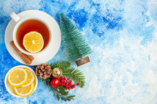 Vista superior de una taza de té pequeñas rodajas de limón de árbol de Navidad en la mesa azul