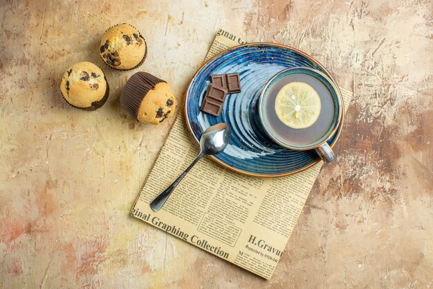 Vista superior de la taza de té con pequeños pasteles dulces sobre fondo claro