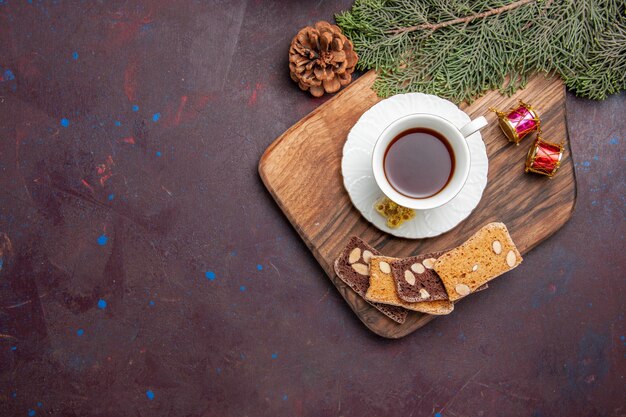 Vista superior de una taza de té con rebanadas de pastel en el espacio oscuro