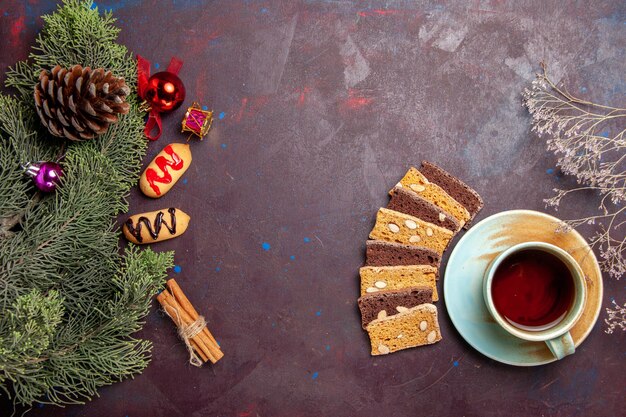 Vista superior de una taza de té con rebanadas de pastel y galletas en el espacio oscuro