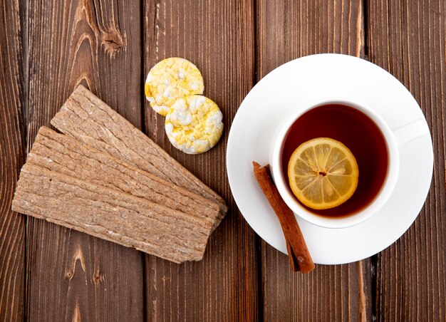 Vista superior de una taza de té con una rodaja de limón y canela con galletas y pan crujiente