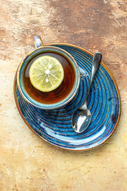 Vista superior de la taza de té con una rodaja de limón sobre el fondo marrón