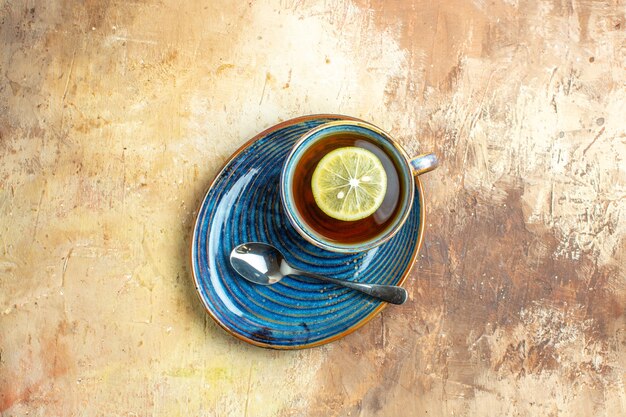 Vista superior de la taza de té con una rodaja de limón sobre el fondo marrón