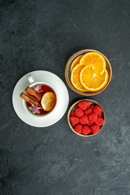 Foto gratuita vista superior de la taza de té con rodajas de naranja y confituras en el té cítrico de frutas de superficie oscura